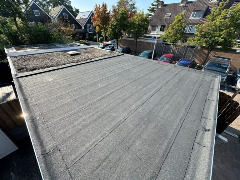 Plat zwart dak met grind op een schuurtje.