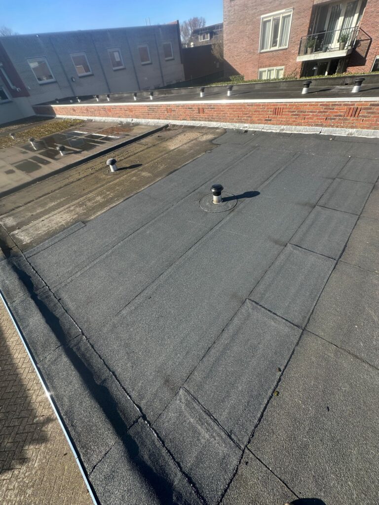 Plat dak van gebouw met ventilatiepijpen.