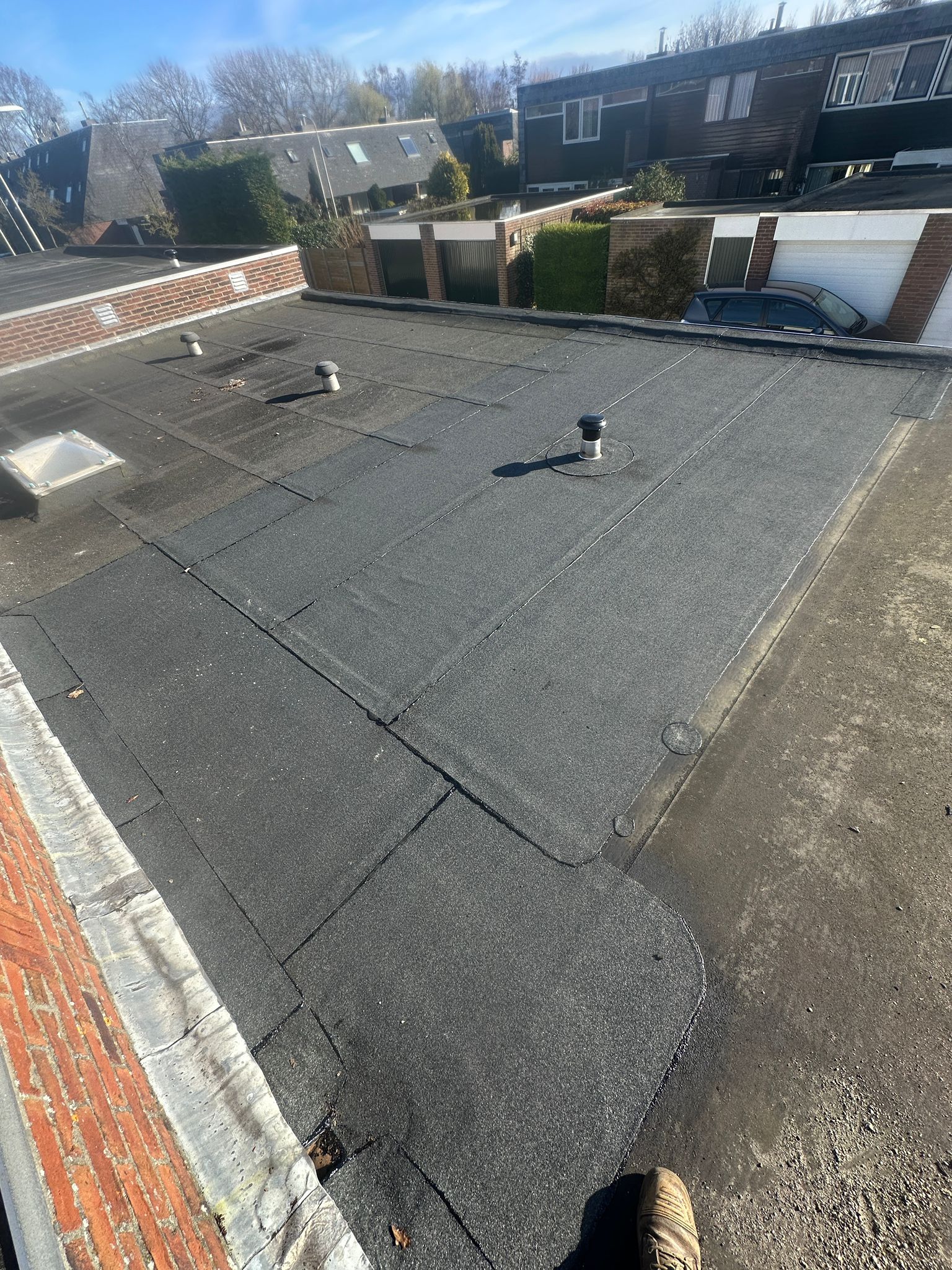 Plat dak van een huis, omringd door rijtjeshuizen.