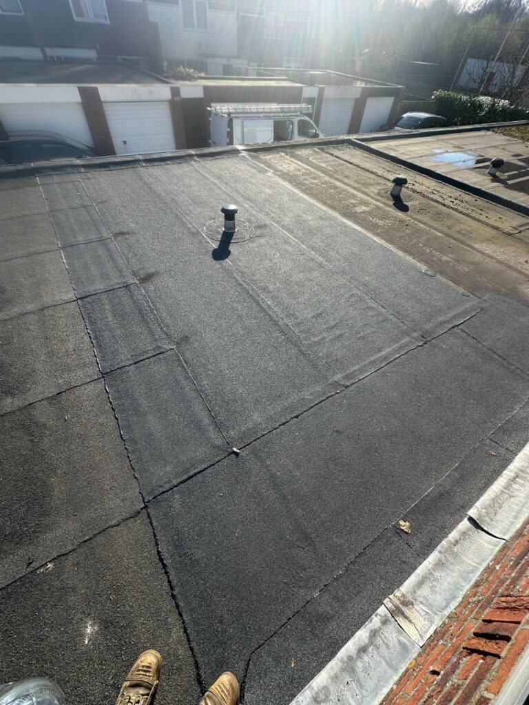 Plat dak met bitumen bekleding onder zonlicht.