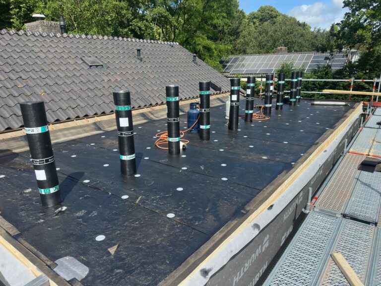Dakisolatie met bitumenrollen en zonnepanelen op achtergrond.