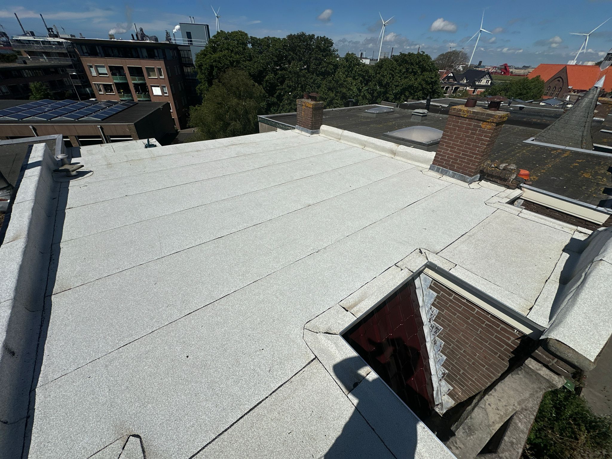 Plat dak met zonnepanelen en windmolens.